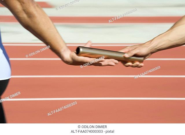 Runners exchanging baton in relay race, cropped