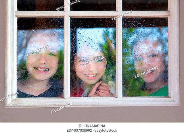 three sister friends looking through the window with a pup and raindrops