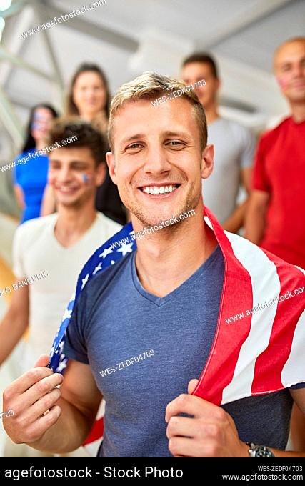 Smiling man holding American Flag in at sports event in stadium
