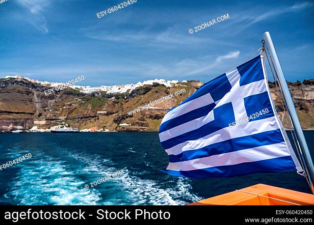 Greek flag on tender boat leaving Fira port on Santorini