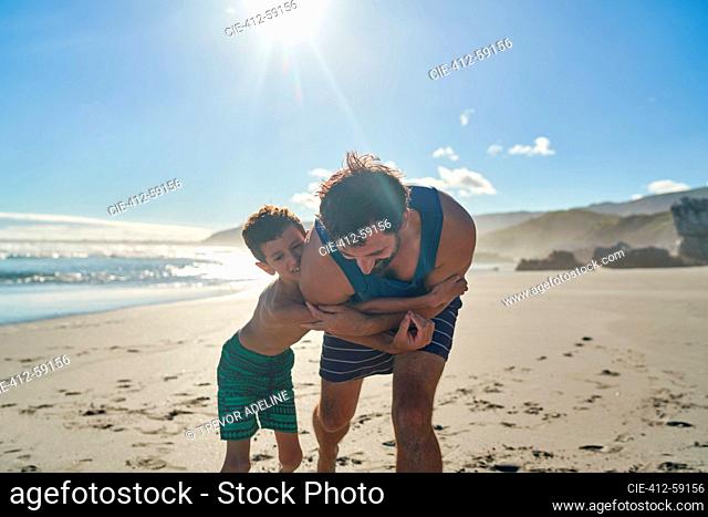 Happy father and son hugging on sunny summer beach