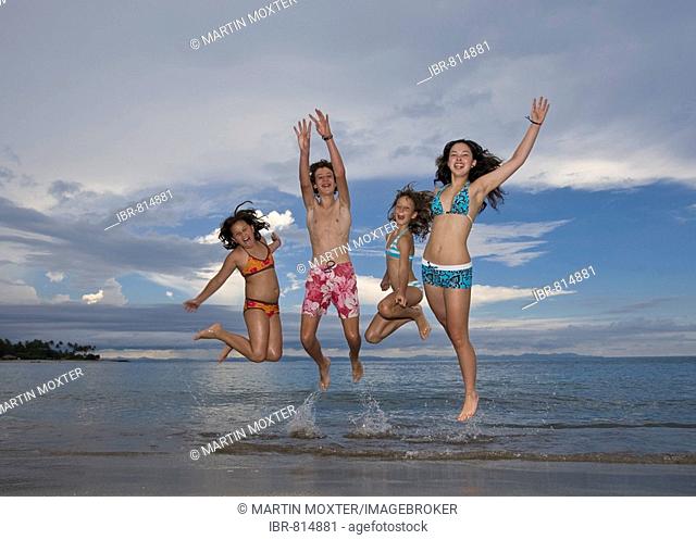 Four children jumping with joy on the beach, Lombok Island, Lesser Sunda Islands, Indonesia, Asia