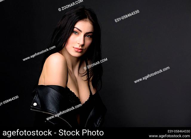 Picture of beautiful brunnette model woman in black lingerie or underwear showing her perfect body while posing for photographer in studio
