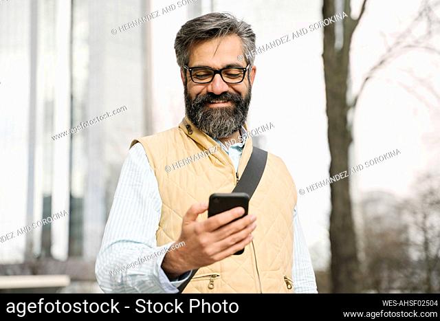 Smiling man using smartphone in the city, Frankfurt, Germany
