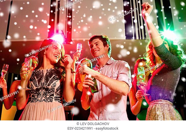 new year party, holidays, celebration, nightlife and people concept - smiling friends clinking glasses of non-alcoholic champagne and beer in club and snow...