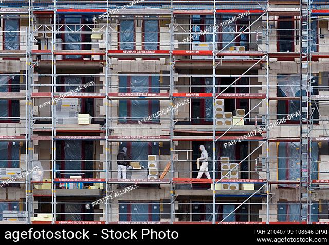 06 April 2021, Brandenburg, Potsdam: Workers walk on scaffolding from a shell at the Havel Quartier construction site. The new quarter with commercial space