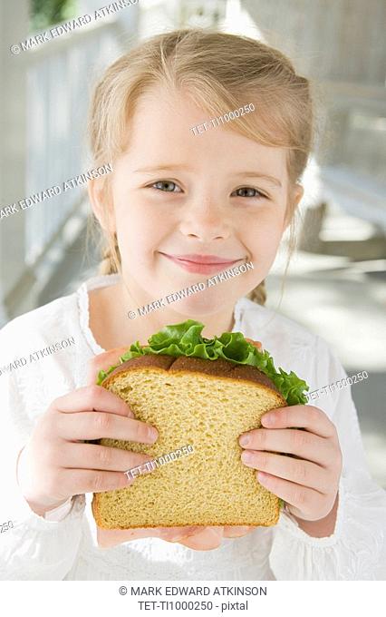 Girl eating sandwich on porch