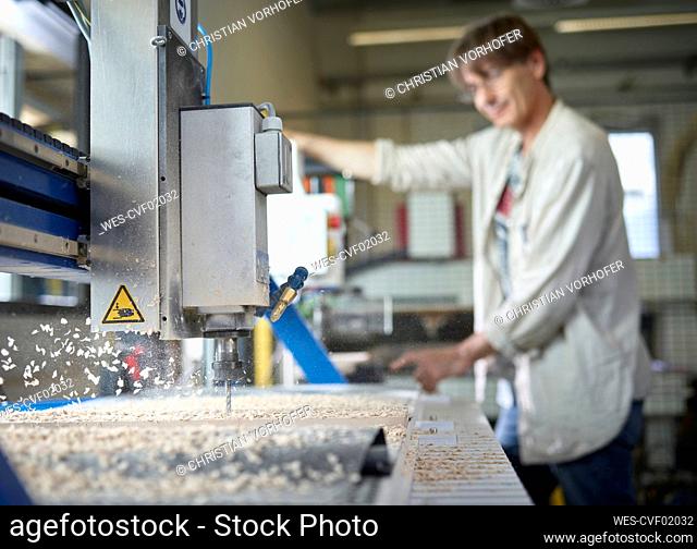 Mature man with CNC machine working in factory