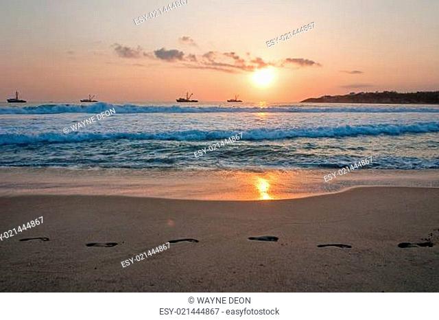 Beach sunset with footprints in the sand