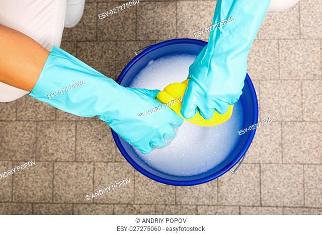 Close-up Of Cleaner Woman Hand Squeezing Cloth In Bucket Filled With Soap Sud