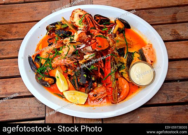 Close up large grilled seafood platter on wooden table, high angle view