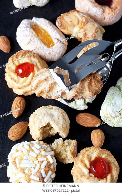 Different sorts of Italian almond cookies and a pastry tong