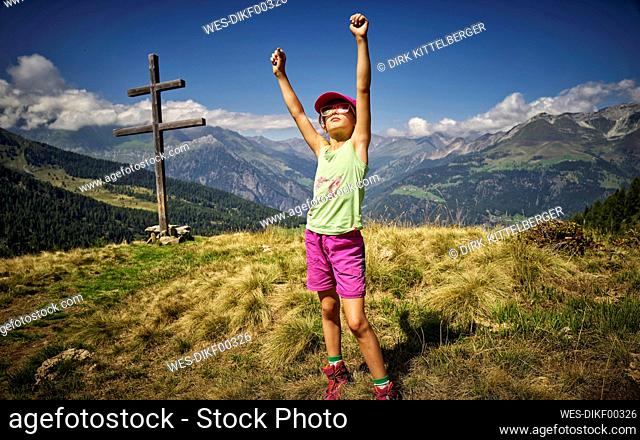 Girl standing at mountaintop in alpine scenery with raised arms, Passeier Valley, South Tyrol, Italy