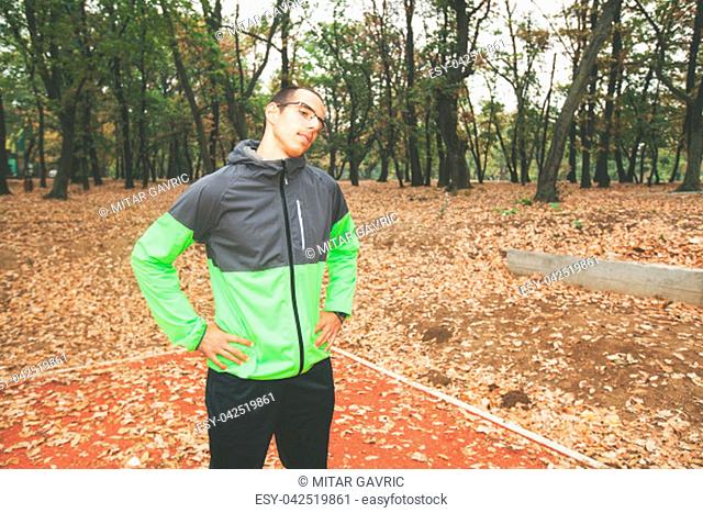 Fitness young man workout at park in autumn morning. Healthy man doing warm up exercise before training