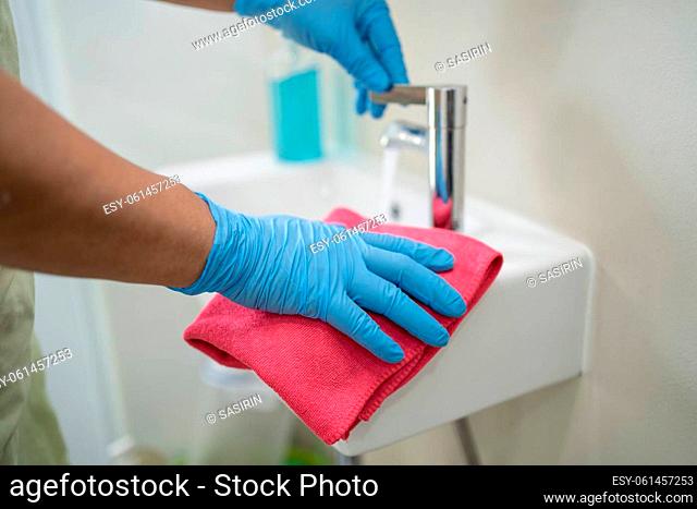 Maid cleaning wash and scrub basin in toilet at home