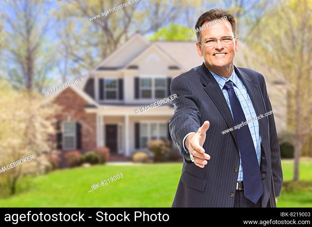 Smiling male agent reaching for hand shake in front of beautiful new house