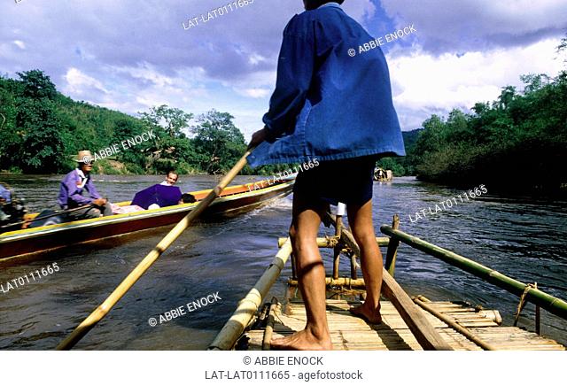 Man with long oar at front of raft steering, contrast to long tailed motor boat passing