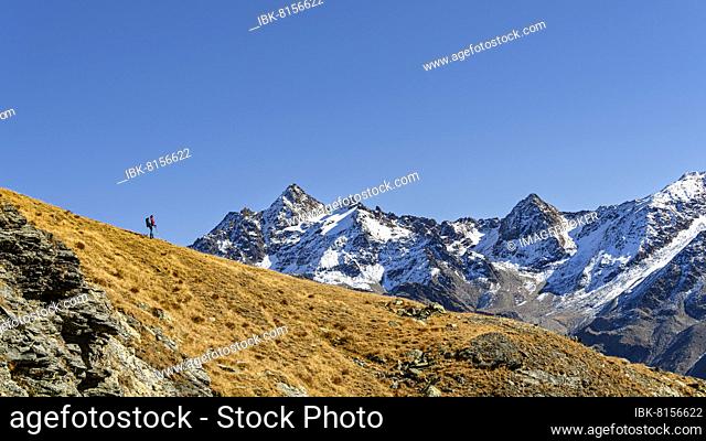 Mountaineer on ridge with snow-covered South Tyrolean mountains in autumnal mountain landscape, Martell Valley, Naturno, South Tyrol, Italy, Europe