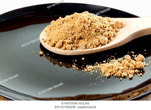 Brown cane sugar in a wooden spoon on the black background. Pure cane sugar for natural. no additives