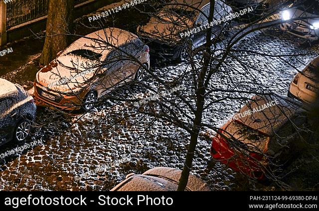 24 November 2023, Berlin: A car drives through a snow-covered street in Karlshorst late in the evening. Photo: Jens Kalaene/dpa