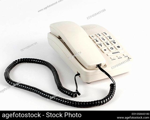 A white telephone with a black cord in a white background
