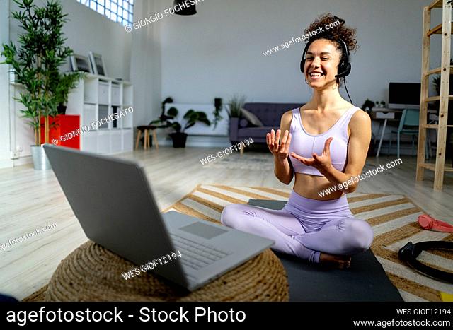 Smiling female influencer gesturing while talking during vlogging through laptop at home