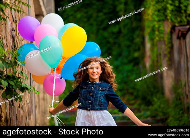 Pretty girl with big colorful balloons walking downstairs in old town