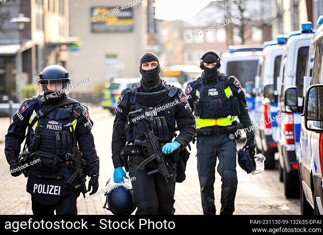 30 November 2023, Lower Saxony, Lehrte: Police officers walk next to police vehicles near a job center. The police have arrested a suspect who is said to have...