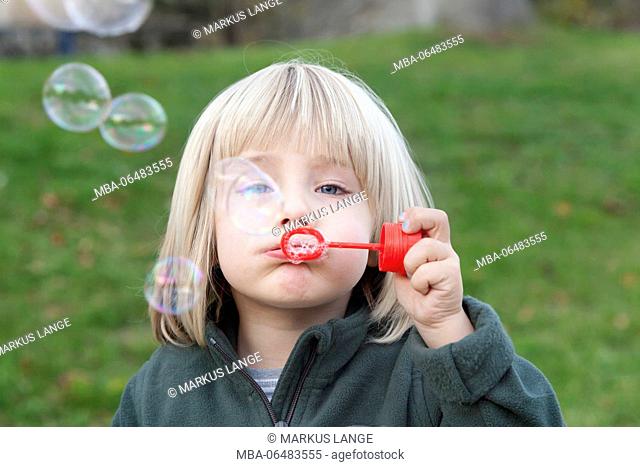 Four-year-old boy puffs soap bubbles
