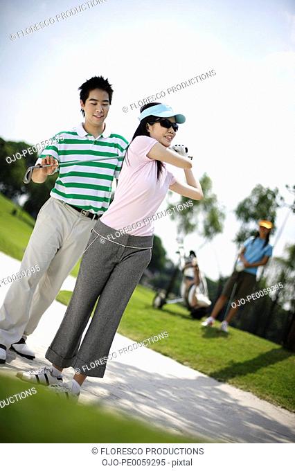 Couple golfing with woman in background