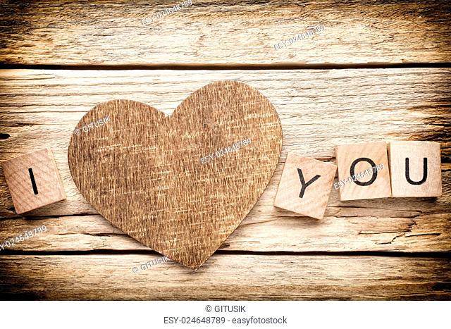 Wood heart on old wooden background - Stock Image. I love you, cast out of wood kubik