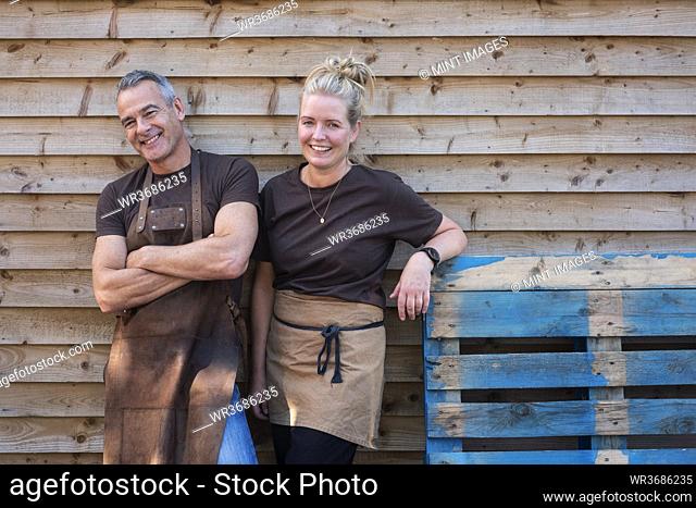 Man and woman in aprons, colleagues taking a break from work, laughing