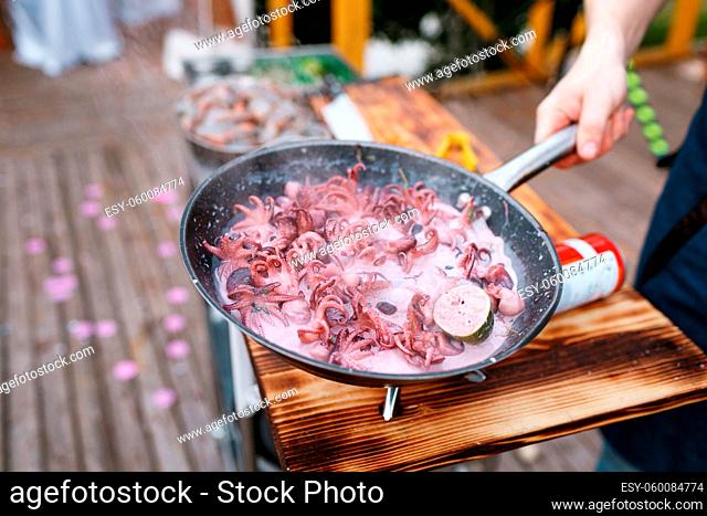 Flambe. Fried seafood and osmanoglu on iron pan. chief cook pours the alcohol and fire. the chef pours hot sauce. the bake outdoors on a portable gas burner