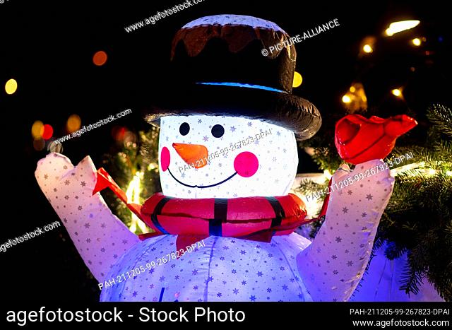 05 December 2021, Bremen: A glowing snowman stands on a Christmas-decorated tractor in the Horn-Lehe district before the start of a drive with lights