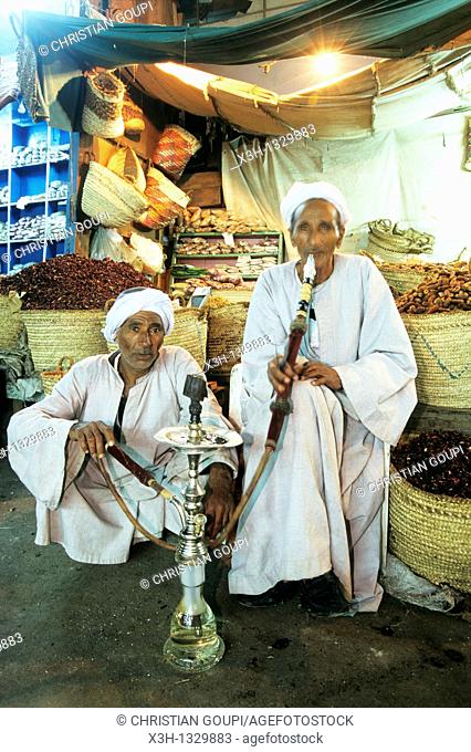 two men smoking hookah in front of their shop, Aswan, Egypt, Africa