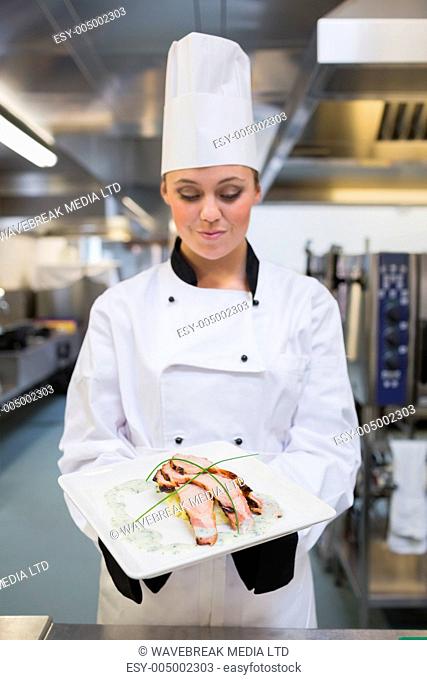Smiling chef looking at her plate in the kitchen