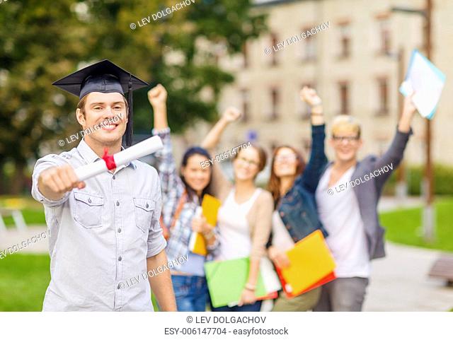 education, campus and teenage concept - smiling teenage boy in corner-cap with diploma and classmates on the back