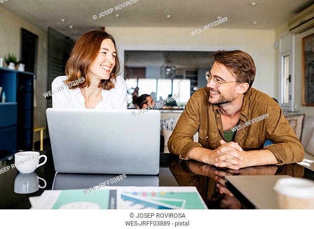 Happy man and woman working together with laptop on table at home