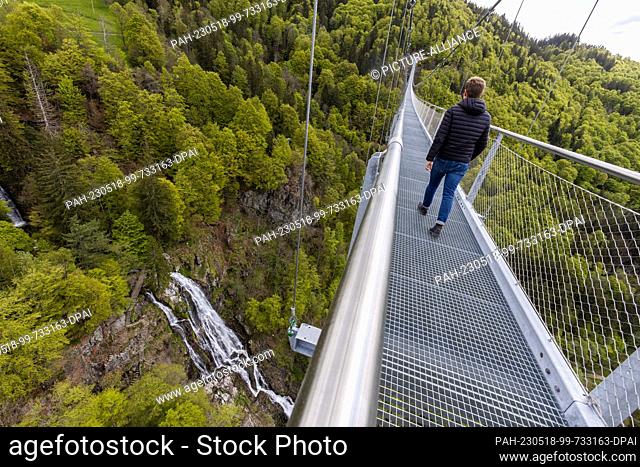 17 May 2023, Baden-Württemberg, Todtnau: A suspension bridge leads over a valley near Todtnauberg while below water the Todtnau waterfalls can be seen