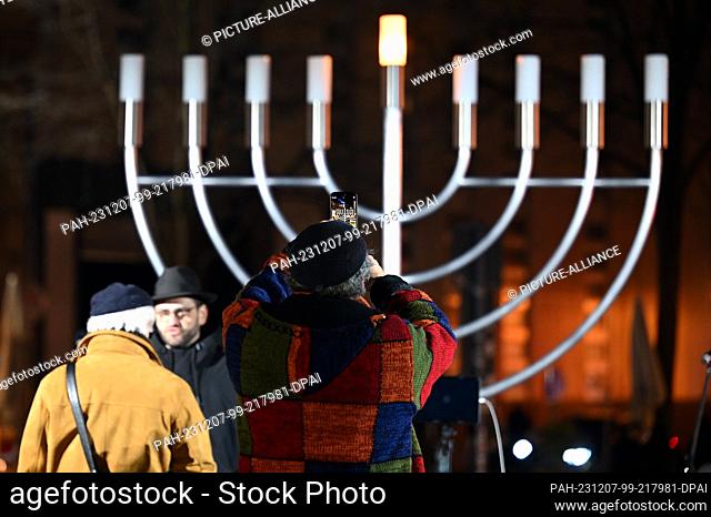 07 December 2023, Saxony, Leipzig: A man photographs the Hanukkah candelabra before the first light is lit. The candlestick was inaugurated at the beginning of...