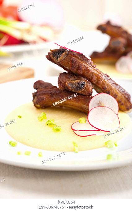traditional Italian roasted pork ribs served on polenta bed, corn cream