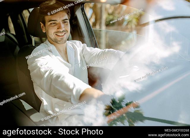 Happy man sitting inside electric car seen through windshield