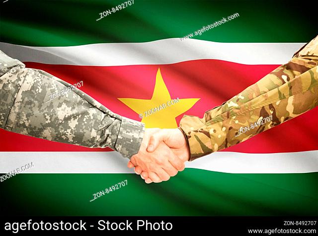 Soldiers shaking hands with flag on background - Suriname