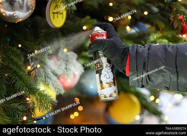 RUSSIA, MOSCOW - DECEMBER 19, 2023: A woman decorates a Christmas tree ahead of the opening of an exhibition of designer Christmas trees in Kuznetsky Most...