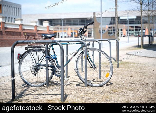 PRODUCTION - 28 April 2021, Hessen, Fulda: A single bicycle stands on the campus of Fulda University of Applied Sciences