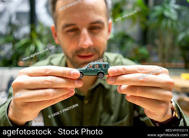 Businessman holding toy car while sitting at cafe