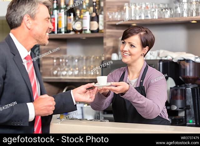 Happy businessman receiving coffee from smiling female waitress