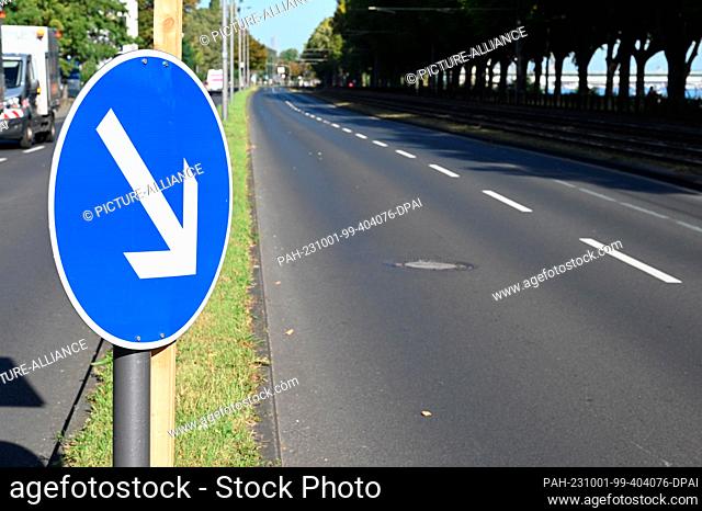 01 October 2023, North Rhine-Westphalia, Cologne: Traffic sign arrow, traffic direction sign white arrow on blue background indicates the direction of travel
