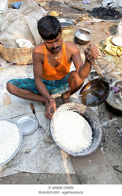 Man in vest and dhoti pouring sugar syrup onto bowl of puffed rice to make prasad, Sonepur Cattle Fair, Bihar, India, Asia