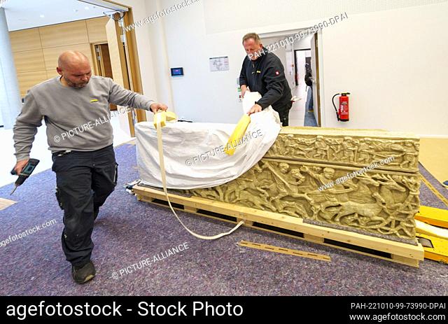 PRODUCTION - 10 October 2022, Rhineland-Palatinate, Mainz: Employees of the transport company unpack the copy of a Roman sarcophagus (3rd-4th century BC) in the...